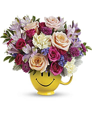 Cheerful smile face flower arrangement in a smiley mug filled with vibrant flowers.