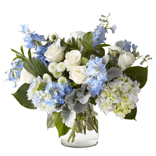 Coastal Blossoms - Elegant blue and white flower arrangement in a glass vase, featuring roses and hydrangeas.